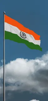 Indian flag flutters against a vibrant blue sky with clouds.