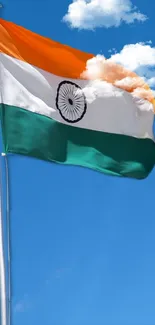 Indian flag waving against a blue sky with clouds.