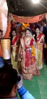 Indian bride walking under a canopy in traditional attire.