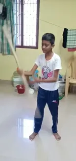 Young boy practicing cricket indoors with bat.