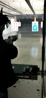 Person shooting at targets in indoor range with empty shells on the floor.