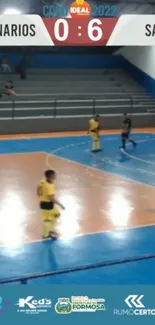 Indoor soccer match with players on vibrant blue court.