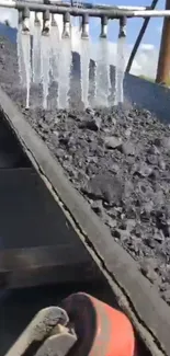 Close-up of coal conveyor with water streams.