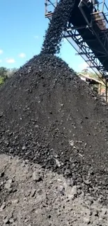 Coal being transported by a conveyor in an industrial site.