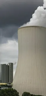 Industrial cooling tower under moody skies with dramatic clouds.