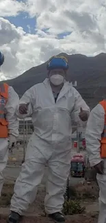 Three workers in safety gear at a cloudy industrial site.