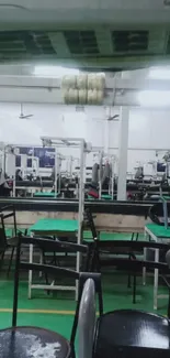 Interior of an industrial sewing facility with equipment and green tables.