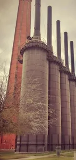 Industrial tower with chimneys against a cloudy sky.