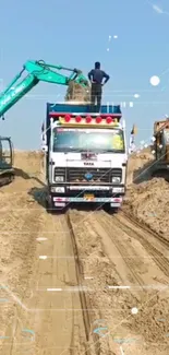 Excavator and truck in a sandy work site under a blue sky.