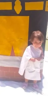 Child in white robe by Kaaba replica.