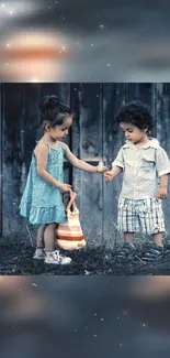 Two young children holding hands on a rustic backdrop.