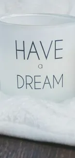 Candle with 'Have a Dream' quote on soft white background.