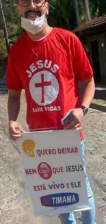 Person holding an inspirational sign with a vibrant red shirt on a street.