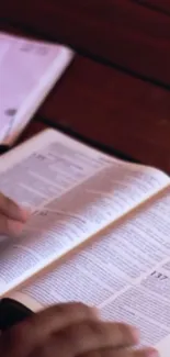 Person turning pages of an open book.