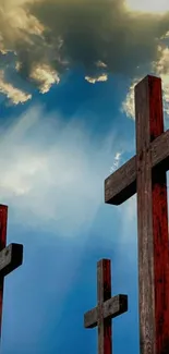 Wooden crosses silhouetted against a blue sky and clouds.