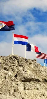 Flags waving on cliff under a bright blue sky.