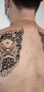 Intricate black tattoo design on a back.