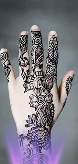 Hand displaying intricate mehndi design on gray background.