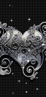 Intricate silver heart design on black background with metalwork swirls.