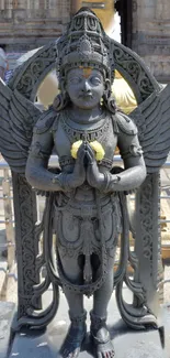 Intricate grey stone statue in outdoor setting.