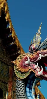 Intricate dragon sculpture on Thai temple roof against blue sky.