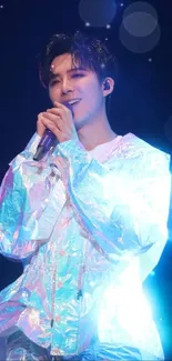 Iridescent singer performing on stage with blue spotlight.