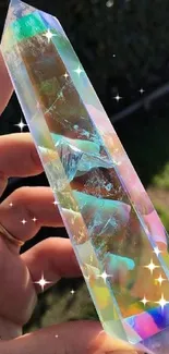 Hand holding an iridescent crystal prism reflecting colorful light.