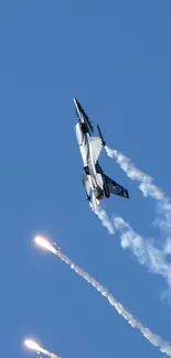 Dynamic jet fighter soaring in blue sky with smoke and flare trails.