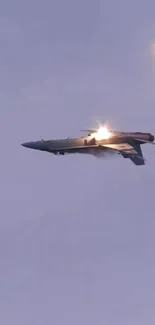 Jet fighter flying in the twilight sky with bright flares and blue backdrop.