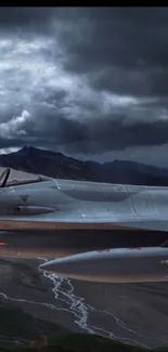 A jet fighter flying over mountains under a dramatic cloudy sky.