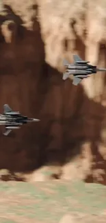 Two jet fighters flying through a desert canyon landscape.