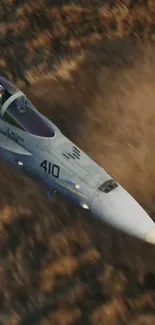 Jet flying over desert landscape with dust clouds.