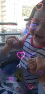 Smiling baby with heart overlays on a light blue background.