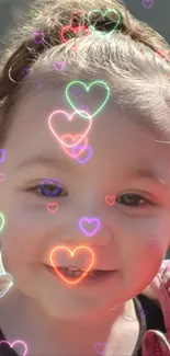 Smiling baby with neon hearts overlay wallpaper.