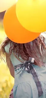 Girl holding balloons in a sunny field.