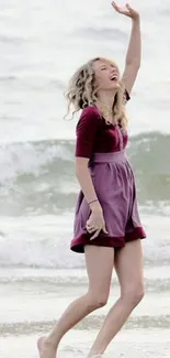 Person joyfully walking on the beach in a magenta dress.