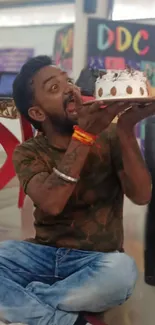 Man joyfully holding cake surrounded by colorful decor.