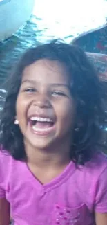 Joyful child laughing in bright pink shirt.