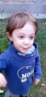 Child smiling in blue hoodie outside.