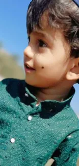 Child smiling in green attire, outdoor setting.