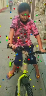 Child on bike with confetti in a vibrant street scene.