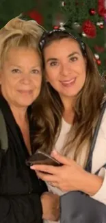 Two women smiling in front of a decorated Christmas tree.