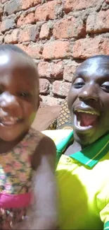 Smiling father and child with brick wall background, capturing joyful family time.