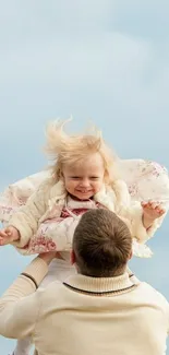 Father lifting child against a blue sky background.