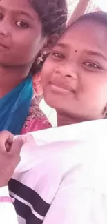 Two young women smiling in a close-up, vibrant and joyful portrait.