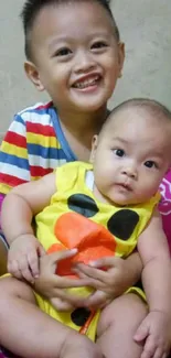 Two smiling kids with colorful outfits on a bright pink bedspread.