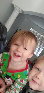 Two happy kids in colorful pajamas smiling at home.