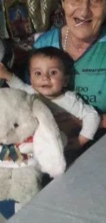 Child with plush toy and family member, smiling.