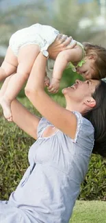 Mother lifts baby joyfully outside.