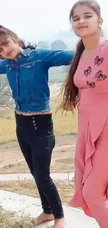 Two girls enjoy an outdoor moment with scenic countryside views.